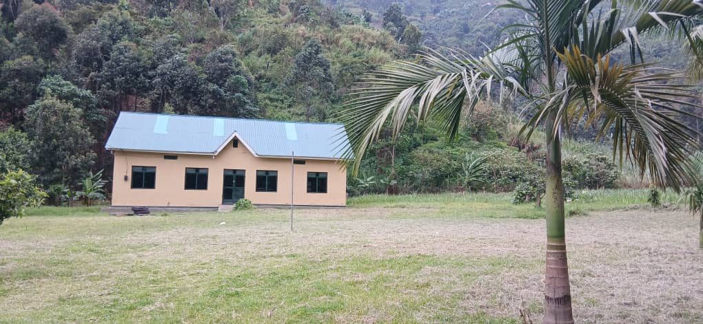 Building set on a grassy compound with forested hillside behind