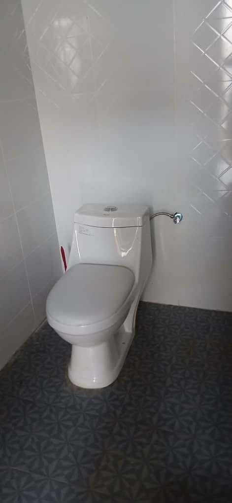 Modern toilet in a white tiled room